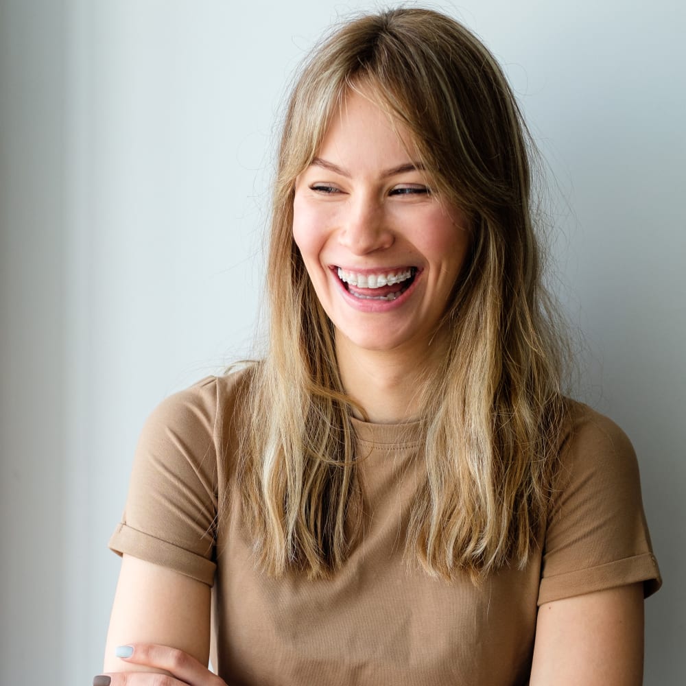 A blonde woman is wearing ceramic braces.