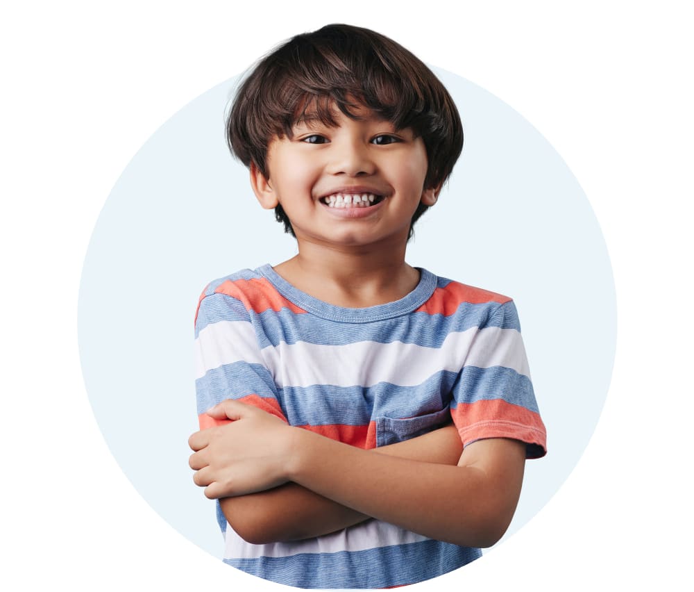 A young boy is smiling and wearing a blue and white striped shirt.