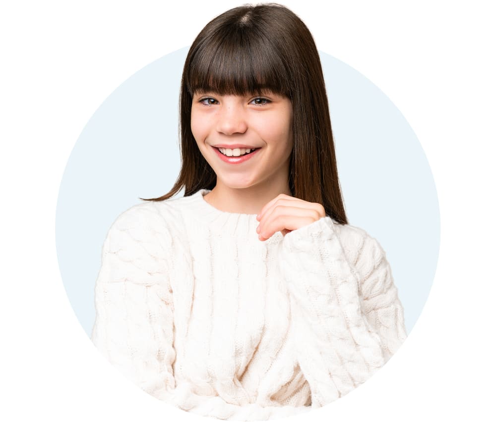 A young girl is smiling and wearing a white sweater.