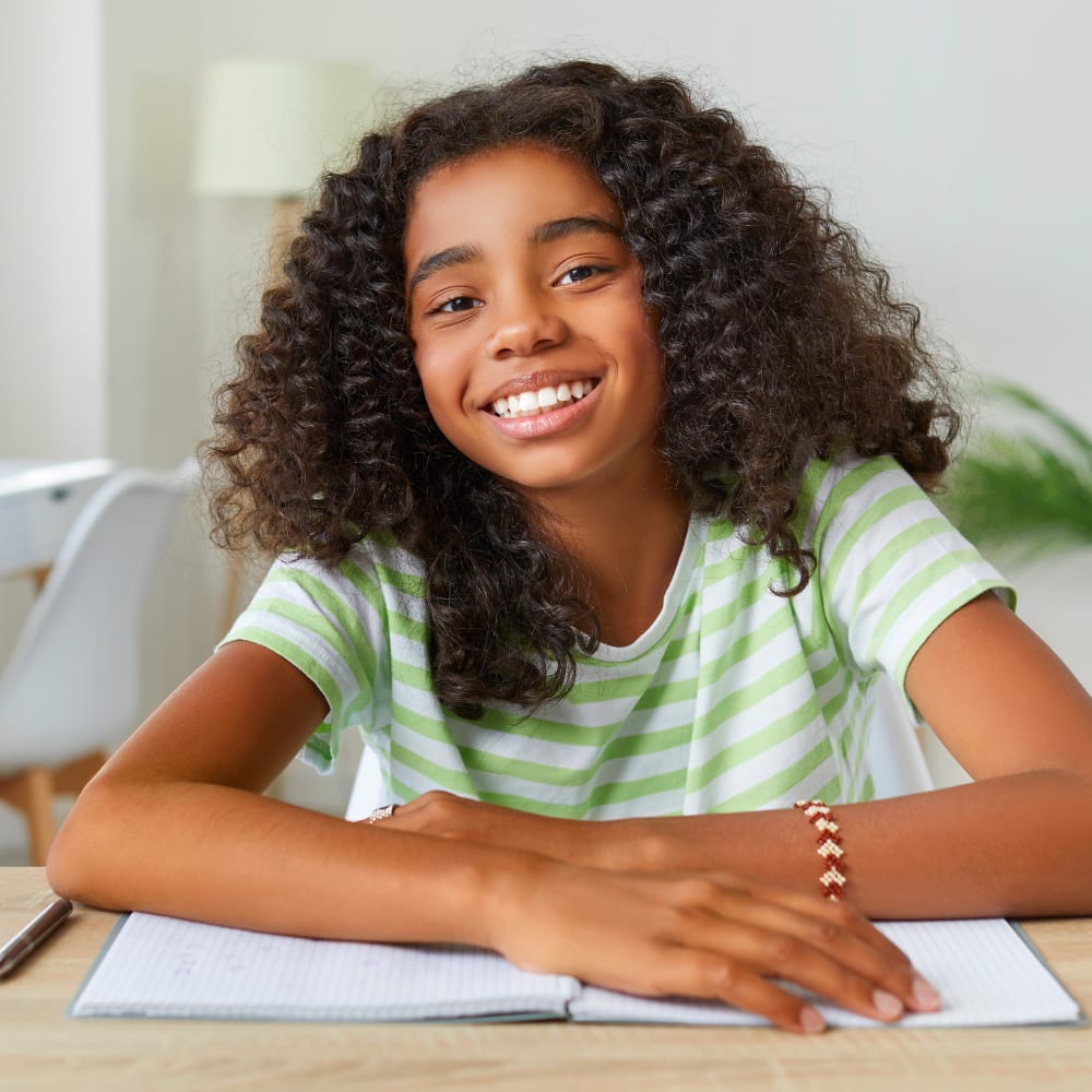 A young girl with curly hair is smiling.