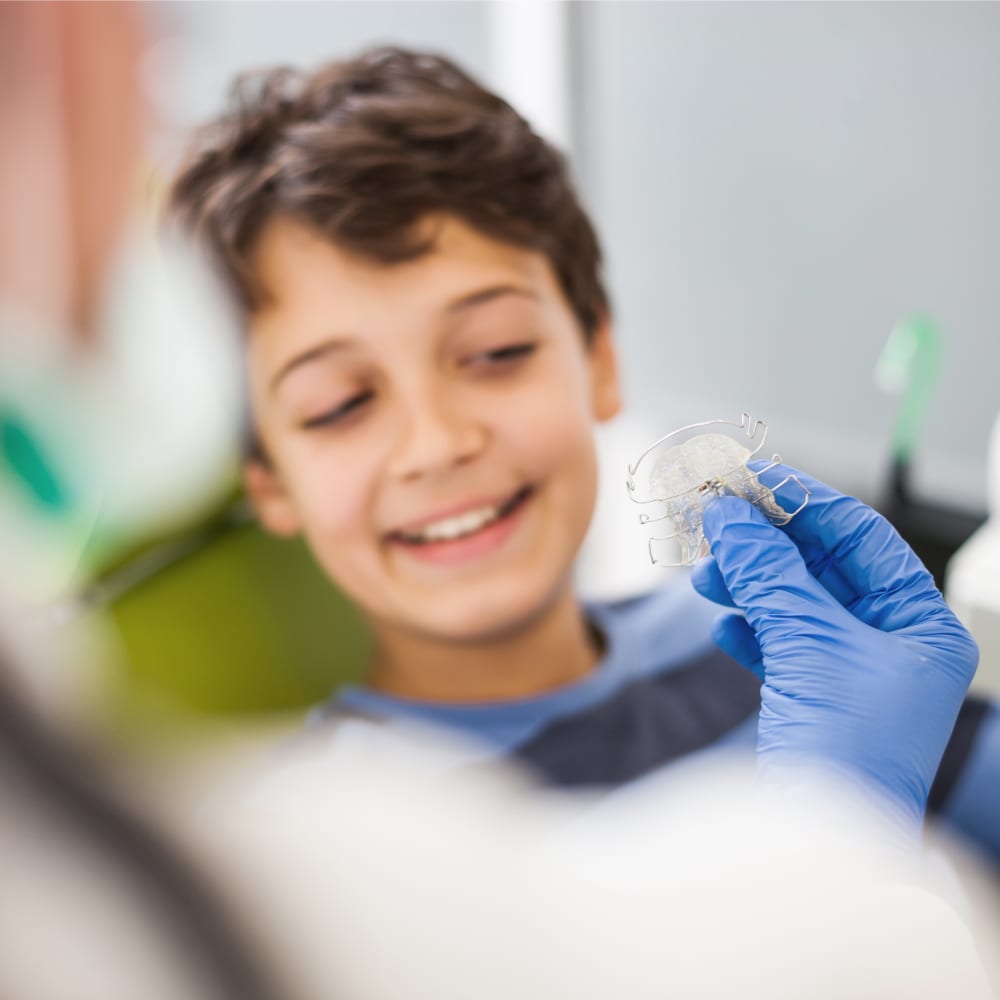 A kid is about to receive a retainer from a dentist.